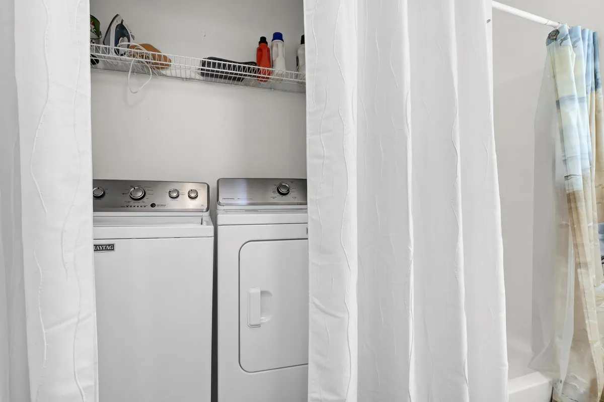A tidy laundry area with a washing machine, dryer, and organized shelving with detergents, evoking a sense of order and convenience.