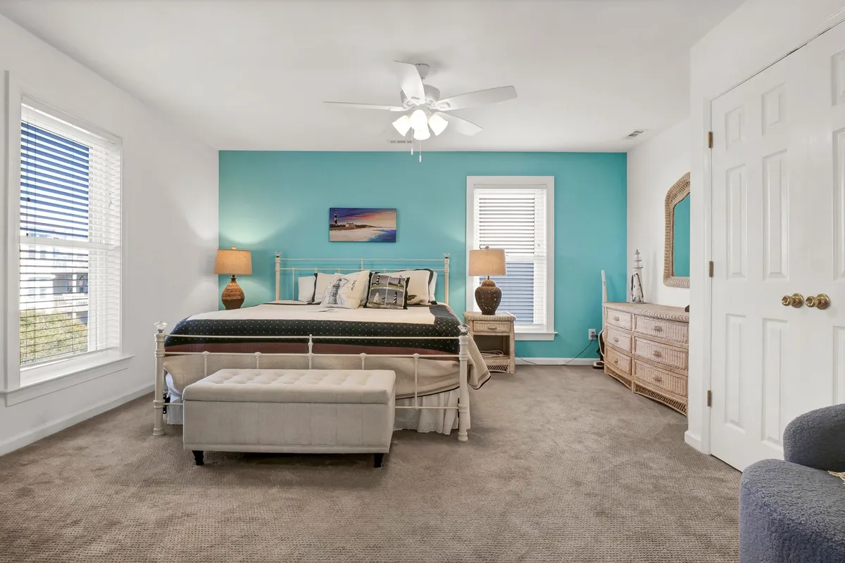 A tranquil bedroom featuring a comfortable bed set against a colorful accent wall, a dresser, and a window that lets in plenty of natural light, creating a relaxing retreat.